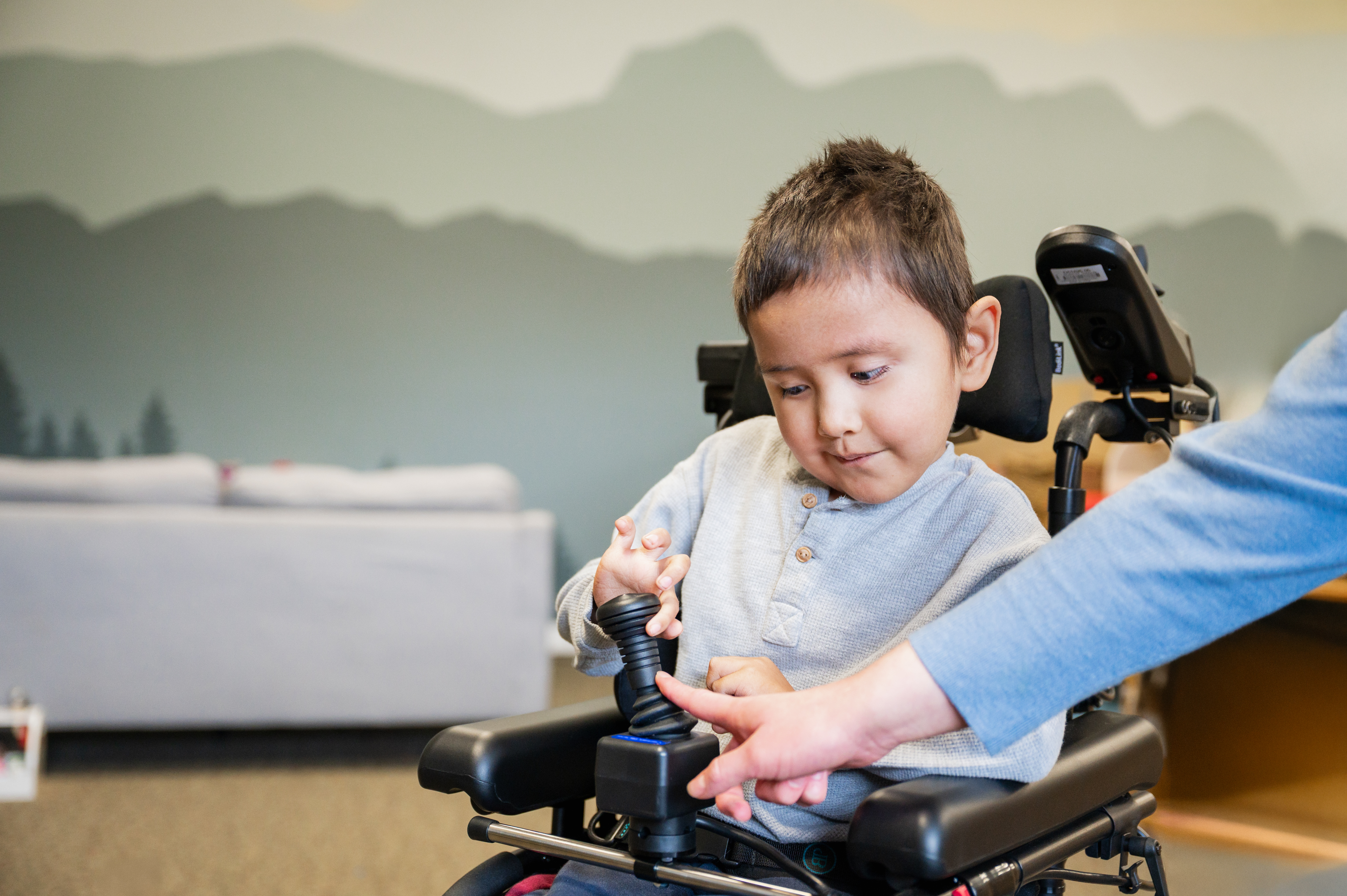 A young child in a wheel chair learning by looking down at what an instruction is pointing at.